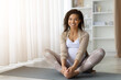 © Anastasiya - Happy pregnant African American woman sitting on yoga mat, smiling while doing stretching exercise, practicing prenatal yoga for health and relaxation at home