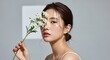 © REMIN KHATUN - Portrait of a woman holding white wildflowers in front of her face softly lit