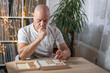 © kittyfly - senior man focused on solving sudoku puzzle on wooden board, Brain exercise, cognitive health, and mental agility in mature age, mental stimulation, brain health