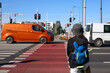 © Iryna - School-age teenager with bike waiting at pedestrian crosswalk, obeying red traffic light while vehicles pass, representing child road safety and responsibility