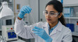 © Artem Zatsepilin - young indian female scientist wearing gloves and goggles working in lab with test tubes. scientific research and analysis, liquid testing. national water quality month. environmental campaign.