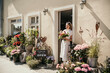 © Westend61 - Smiling woman with bunch of flowers standing near doorway of flower shop