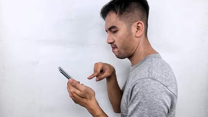 Shocked young Asian man staring at his smartphone screen in disbelief.