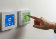 © Ismatara - Finger adjusting the temperature on a smart thermostat, controlling the home heating system for optimal comfort and energy saving