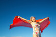 © Connect Images - Woman in floral swimsuit joyfully holds a vibrant red shawl against a clear blue sky. Kepaniwai Park, Wailuku, Hawaii