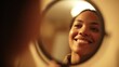 © Justlight - Beautiful young woman is smiling while looking at her reflection in a round mirror, enjoying a moment of self care and confidence in her bathroom