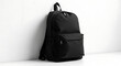 © elkhan - A black backpack rests against a white wall, showcasing its simple design and practical features.