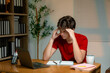 © PaeGAG - Young male experiencing temple pain while typing on laptop, stressed student preparing for academic work in home workspace