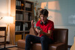 © PaeGAG - Young man sitting on home couch, showing surprised expression while scrolling smartphone screen, experiencing sudden joy from received message