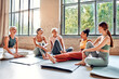 © HBS - Diverse women relaxing after workout on yoga mats in a bright spacious studio, sharing smiles and conversation. Wellness, motivation, friendship, and community in a peaceful fitness environment.