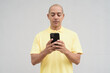 © Ranta Images - Portrait of bald Hispanic man using phone against plain white background wall