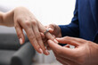 © New Africa - Making proposal. Man putting engagement ring on his girlfriend's finger indoors, closeup