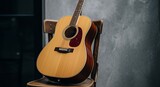 Acoustic Guitar on Wooden Chair Against Grey Wall