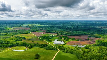 Wall Mural - forested fields and hills with fast-moving clouds creating shadows over rural, panoramic high angle
