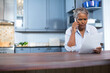 © wavebreak3 - Senior African American woman holding smartphone, reading document at kitchen island, copy space