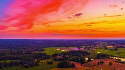 Wall Mural - Vivid magenta sky over fields and rolling hills at dusk, smooth cloud texture reflects across sky and forest