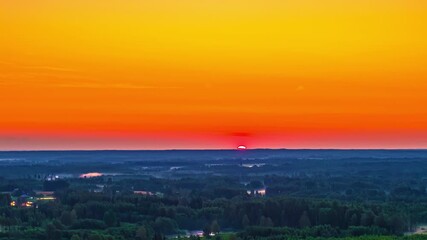 Wall Mural - Fiery orange sunrise glow over distant farmland and fields, space for text in sky above