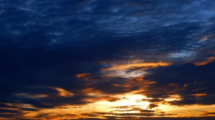 Wall Mural - A sunset time lapse shows golden light piercing through dark stormy clouds, casting fiery streaks across the sky, reflecting the powerful and shifting moods of weather in nature’s evening display.
