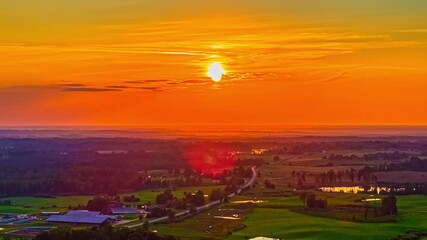 Wall Mural - Setting sun over rural farmland under vivid evening sky, warm golden hues cast across countryside, space for text in sky
