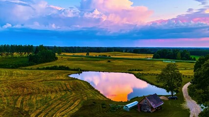 Wall Mural - Golden hour sky reflects over quaint pond by barn at center of farmland