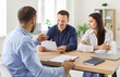 © Studio Romantic - Two customers meeting with loan adviser, mortgage broker or bank finance consultant. Young couple husband and wife sitting at office desk and reading terms of contract agreement that manager offers