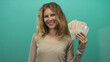 © Krakenimages.com - Woman enjoying money while smiling in british campaign shows blonde young investor holding cash and pound notes on studio green background.