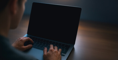 Wall Mural - focused work: a person is hunched over a laptop computer, lost in thought as they work on an importa