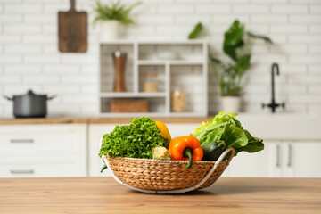 Wall Mural - Wicker basket with different fresh vegetables on wooden kitchen counter