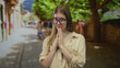 © Krakenimages.com - Young blonde woman with hands pressed together for prayer on sunlit cobblestone narrow old town street; hope faith.