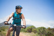 © WavebreakMediaMicro - Male cyclist riding mountain bike along dusty dirt trail wearing helmet, hydration pack, gloves