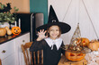 © anatoliycherkas - Smiling girl wearing witch costume posing with carved pumpkins for halloween