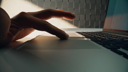 Wall Mural - Macro fingers swiping touchpad laptop in office environment. Freelancer working