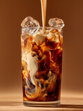 Refreshing glass of iced coffee with milk pouring in, creating beautiful swirling patterns in the dark liquid with ice cubes, isolated on a warm brown background