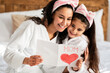 © Prostock-studio - Adorable girl greeting her happy beautiful mom, celebrating Mothers day together at home, wearing white bathrobes and hair bands, spending beauty day in spa hotel, closeup portrait, copy space