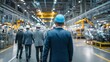 © eric - Business Executives in Hard Hats Touring Modern Automotive Manufacturing Plant with Automated Robotic Arms