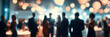 © sornram - A lively gathering of people in formal attire, surrounded by warm ambient lights, celebrating an event or enjoying a night out with friends.
