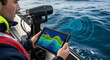 © Cliff - Close-up of engineer with planset with sonar of reconnaissance boat in action monitors data in real time which emits sound waves into seawater revealing contours of seabed, sea and ocean research