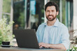 © deagreez - Happy young man using laptop outdoors enjoying a sunny day, representing casual lifestyle and business aspirations