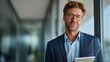 © liliyabatyrova - Young businessman stands confidently inside modern office space during daylight while holding a tablet