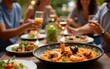 © wu - Outdoor dinner with friends features seafood paella. Festive atmosphere, warm inviting evening. People enjoy fresh dish together. Traditional Spanish cuisine, delicious food with prawns, mussels,