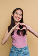 © bodnarphoto - Smiling young woman making a heart shape with her hands.