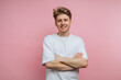 © bodnarphoto - Young man in white t-shirt smiling with arms crossed on pink background.