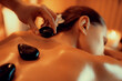 © InfiniteFlow - Closeup hot stone massage at spa salon in luxury resort with warm candle light, blissful woman customer enjoying spa basalt stone massage glide over body with soothing warmth. Quiescent