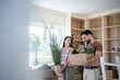 © Migma_Agency - Happy couple carrying plants and boxes into new home