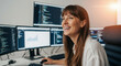 © Milan - Happy female programmer laughing while working on multiple computer monitors. Joyful software developer enjoying her job in a modern office.