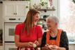 © RooM The Agency - Happy Mother and adult daughter standing side by side in a kitchen making bread