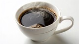 A close-up shot of a hot espresso in a white mug with roasted coffee beans scattered nearby