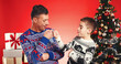 © peopleimages.com - Christmas, fist bump and father with child in studio for celebration, support and holiday season. Happy man, son and festive event for xmas vacation, bonding and December together on red background