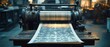 © Aleksandra - Old vintage printing press machine on wooden table with sheet of printed patterned paper rolling out in dimly lit workshop