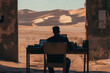© Zstudio - Focused man working on a laptop from a rustic office desk with a breathtaking view of desert sand dunes, embodying the digital nomad lifestyle and solitude